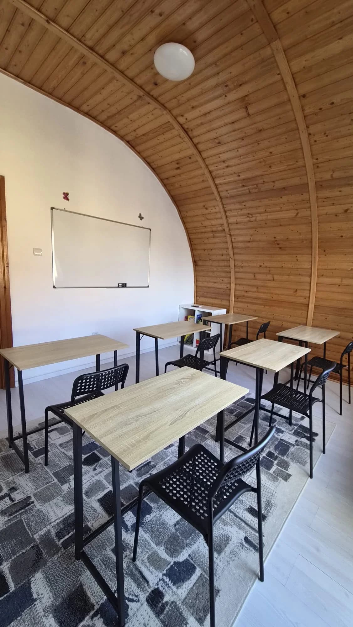 Sala de cursuri PascuPas, cu tavan de lemn arcuit în formă de cort, mese individuale și tablă albă